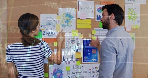 Creative team collaborating on corkboard with brand sketches, sticky notes and data overlay