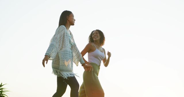 Two African American Women Walking Outdoors Holding Hands at Sunset - Download Free Stock Images Pikwizard.com