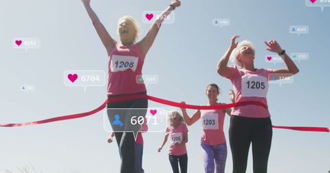 Senior women participating in a race celebrate as they cross the finish line, highlighting both physical achievements and social media engagement reflected by digital notifications around them, symbolizing online recognition and positivity. Could be used for promoting healthy lifestyles, community events, or social media engagement concepts.