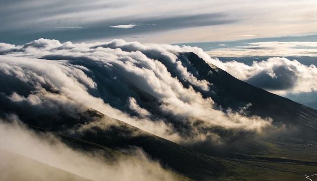 Clouds Cascading Over Alpine Ridge, Sunlit Peaks and Mist-Filled Valleys