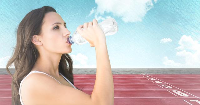 Female athlete drinking water on a race track under a clear sky with clouds in the background. Depicts hydration, fitness, and outdoor sports. Ideal for use in promotional materials for sports events, fitness campaigns, hydration products, or health and wellness content.