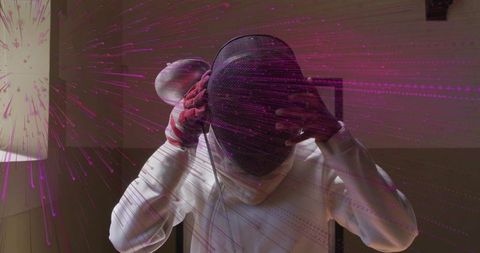 Woman putting on fencing mask and jacket preparing for training with bold magenta light