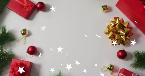 Festive flatlay with red gift boxes gold bow red baubles and evergreen sprigs on white