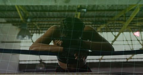 Female boxer resting on ring ropes in gym with determination