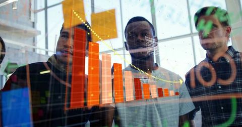 Team collaborating on declining orange bar chart on glass dashboard in modern office