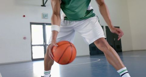Basketball player dribbling ball indoors in gym