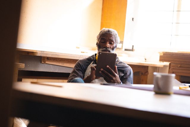 Mature African American Carpenter Using Digital Tablet in Workshop - Download Free Stock Images Pikwizard.com