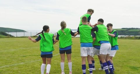 Soccer Team Celebrating on Coastal Field in Neon Green Bibs