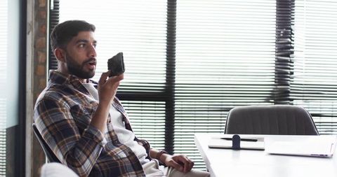 Young Professional Interacting with Smartphone in Modern Office Setting