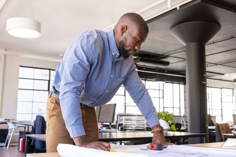 Architect Reviewing Blueprints in Modern Office Workspace
