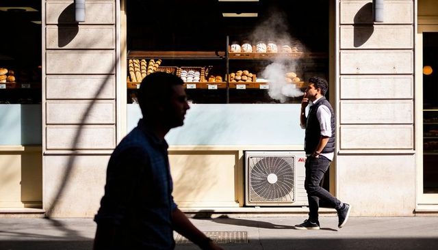 Walking man smoking past bakery window with pastry display and dramatic sidewalk shadows