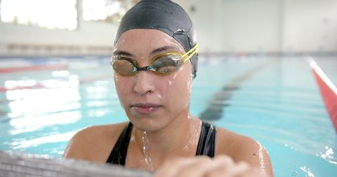 Focused swimmer resting at indoor poolside after intense training
