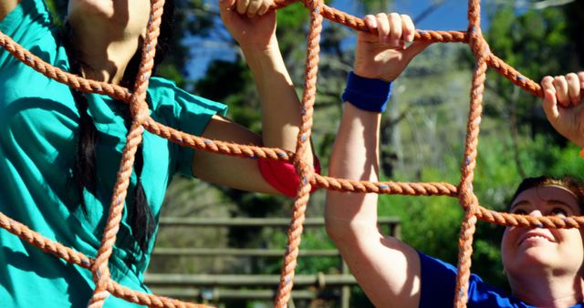 Two children are engaged in playful activity on a rope climbing structure outdoors, with copy space - Download Free Stock Photos Pikwizard.com