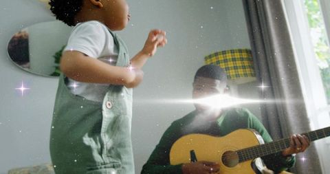 Toddler reaching while father playing guitar in cozy home bonding moment