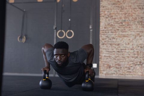 African american man performing kettlebell push-ups in minimalist gym strength training