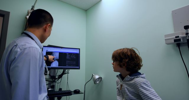 Pediatrician showing x-ray results to a young patient in a medical office. Good for illustrating healthcare consultations, pediatric check-ups, medical diagnoses, doctor-patient interactions, and family health content in blogs, websites, and educational materials.