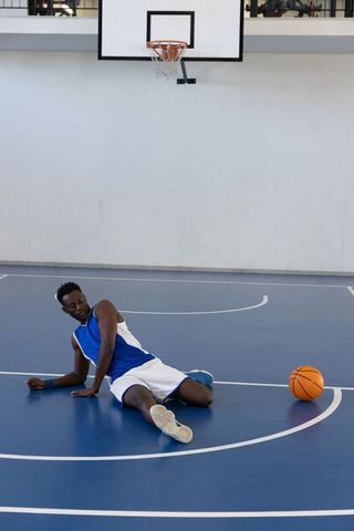 African american athlete sitting on indoor basketball court