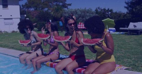 Poolside friends laughing and eating watermelon in colorful summer swimsuits