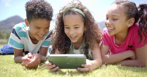 Children Enjoying Smartphone Outdoors in Sunlit Field