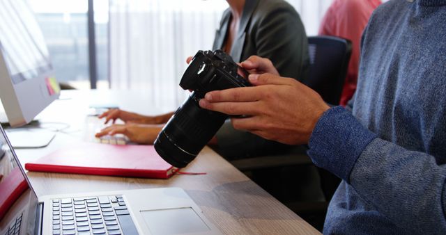 Photographer Reviewing Camera Settings in Office Environment - Download Free Stock Images Pikwizard.com