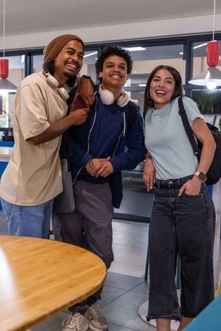 College students smiling and relaxing in campus lounge wearing headphones and backpacks