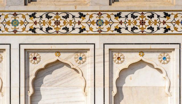 Sunlit mughal marble facade featuring pietra dura floral frieze and cusped arches