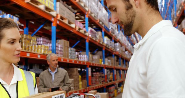 Warehouse workers scanning and managing packages in a distribution center. Ideal for content related to logistics, supply chain management, warehouse operations, and professional teamwork.