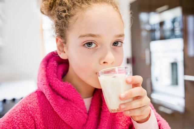 Portrait of cute girl drinking milk in kitchen at home