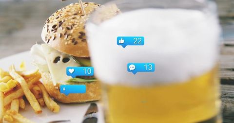 Seeded bun burger melting cheese with fries and beer featuring social media notifications