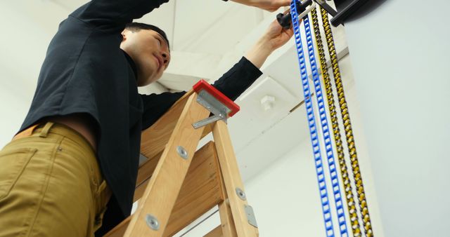 Technician installing cable on wooden ladder, indoor workspace - Download Free Stock Images Pikwizard.com