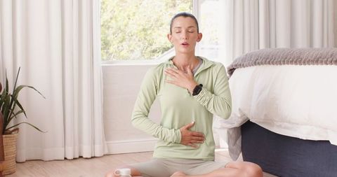 Woman practicing mindful breathing exercise in relaxing home setting