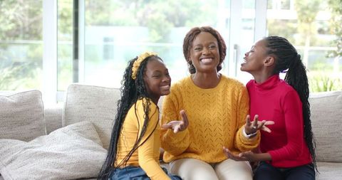 African American Mother and Daughters Laughing Together on Cozy Bright Living Room Sofa