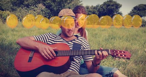 Joyful couple making music in sunny outdoors with balloons overlay
