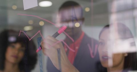 Team Analyzing Business Strategies on Glass Wall