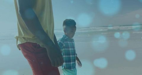 African american father and son walking shoreline at low tide scanning wet sand