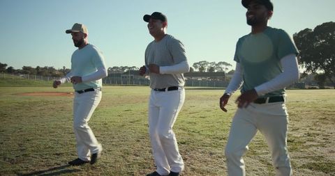 Jogging baseball teammates on sunlit diamond practicing warmups and building teamwork in morning