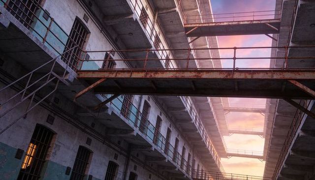Abandoned prison atrium featuring rusted catwalks and sunset glow