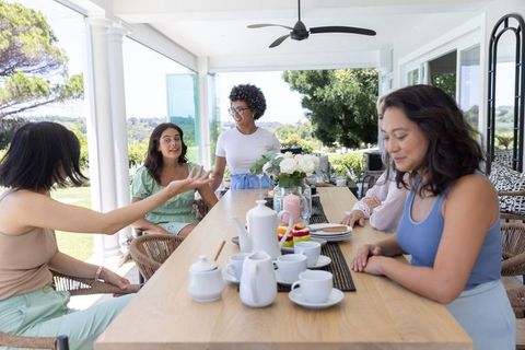Multigenerational diverse women enjoying alfresco tea party on sunny terrace brunch