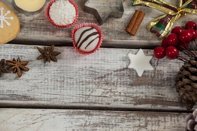 Christmas decorations and sweets arranged on a rustic wooden table. Ideal for holiday-themed promotions, festive greeting cards, seasonal blog posts, and social media content. The image evokes a cozy and warm holiday atmosphere.