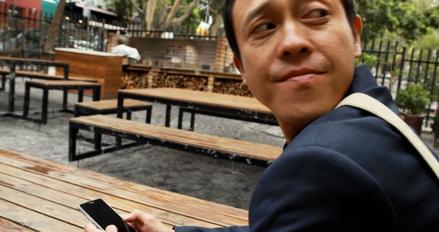 Man holding smartphone at outdoor cafe table - Download Free Stock Images Pikwizard.com