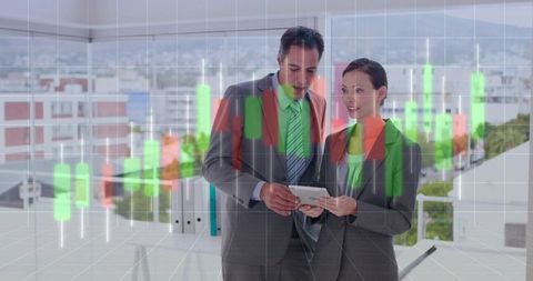 Business colleagues analyzing market candlestick charts on tablet in glass-walled office