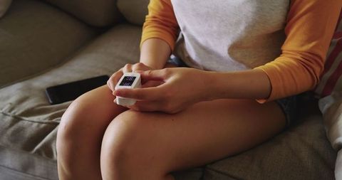 Young woman monitoring health with pulse oximeter at home