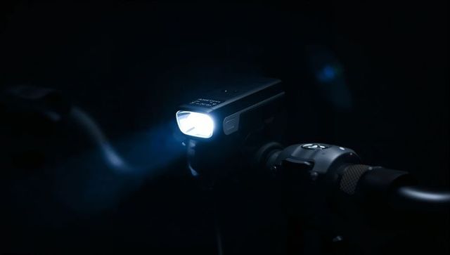 High-contrast led bicycle headlight beaming blue light on handlebar mount at night