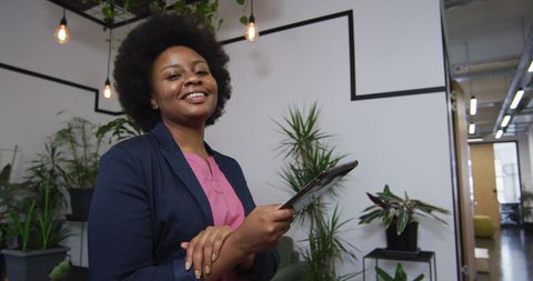 Confident Professional Woman Holding Tablet in Modern Office Space