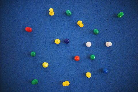 Colorful pushpins on blue corkboard background