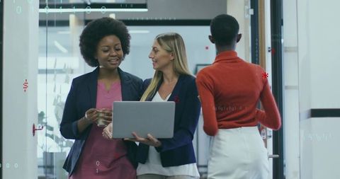 Three women collaborating with laptop in modern office corridor corporate teamwork