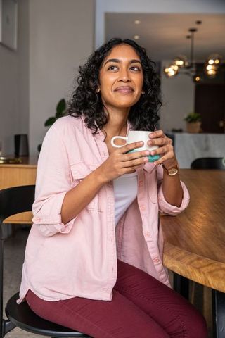 Relaxed South Asian Woman Enjoying Coffee in Contemporary Kitchen
