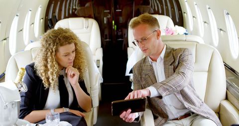 Business Professionals Collaborating on Tablet in Private Jet
