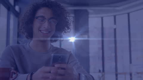 Happy Man with Curly Hair Using Smartphone in Modern Cafe