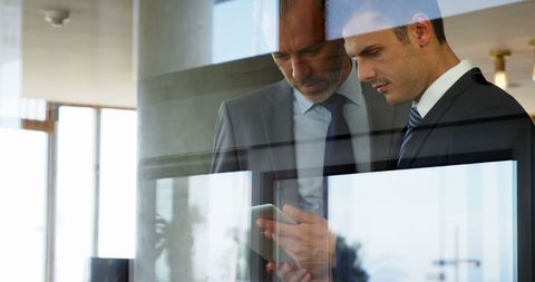 Businessmen Collaborating with Tablet in Modern Setting